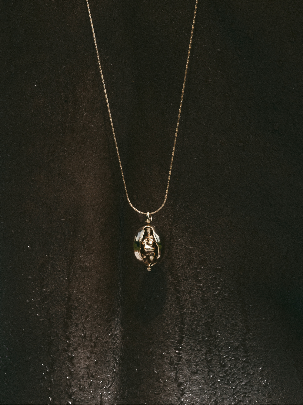 Close-up of a Carina Hardy fine yellow gold Woman of Willendorf necklace on a model, with intricate design inspired by natural elements.