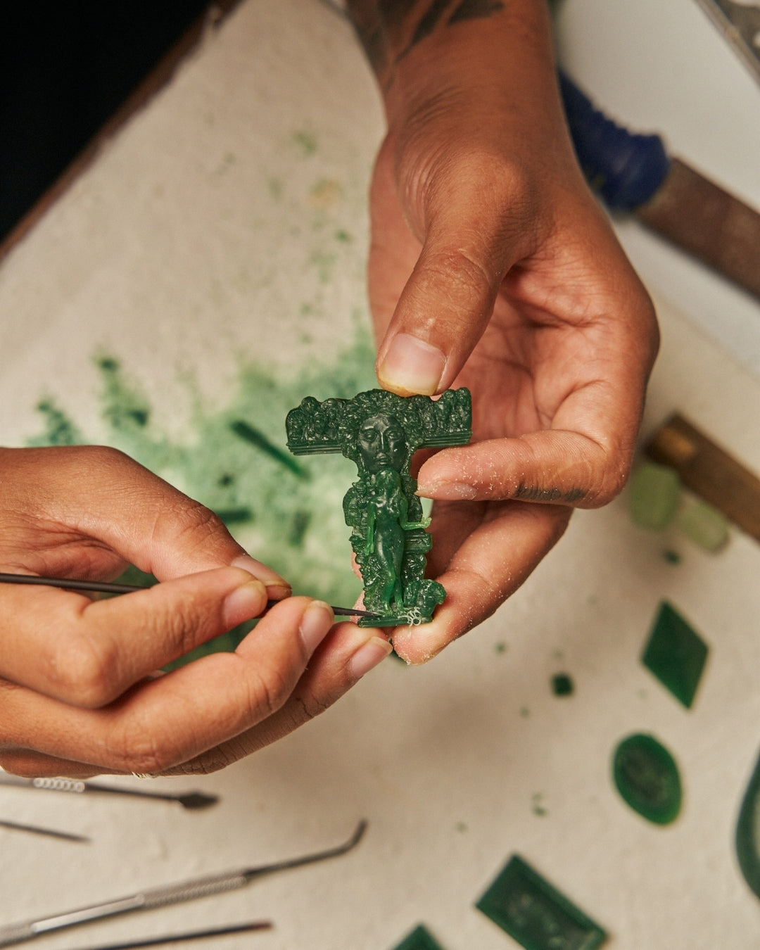 Close-up of a craftsman’s hands holding green wax for Carina Hardy fine jewelry line. Intricate process behind the luxury pieces. Discover the artistry, view the collection.