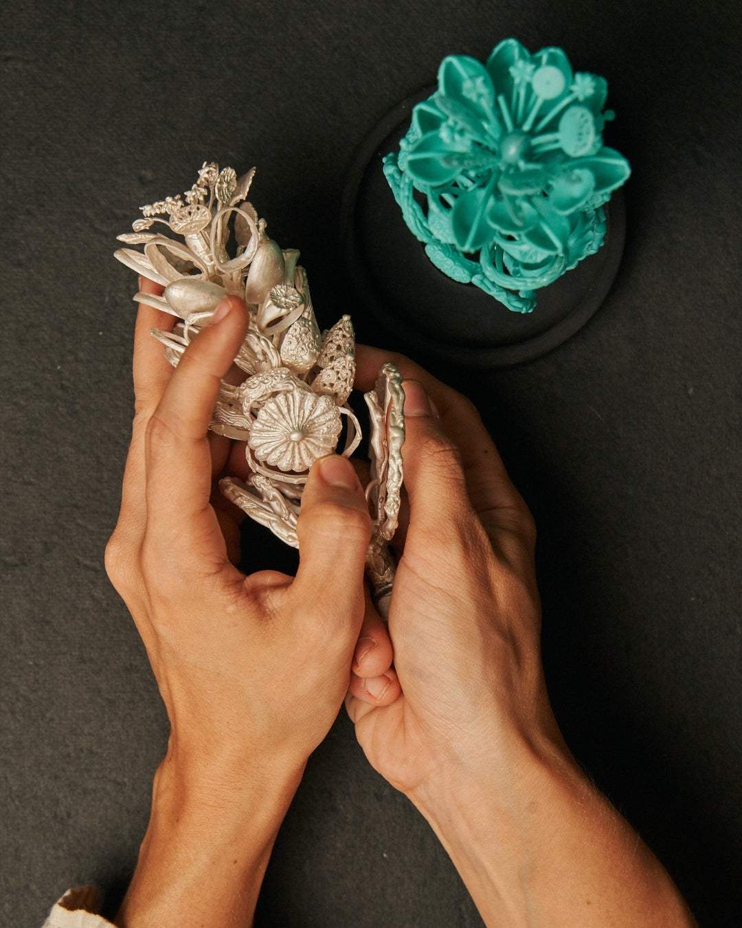 Hands cusping a silver casting tree, showing the process of jewelry making from wax to precious metals. Peeking at the craftsmanship behind Carina Hardy’s fine jewelry. View the collection.