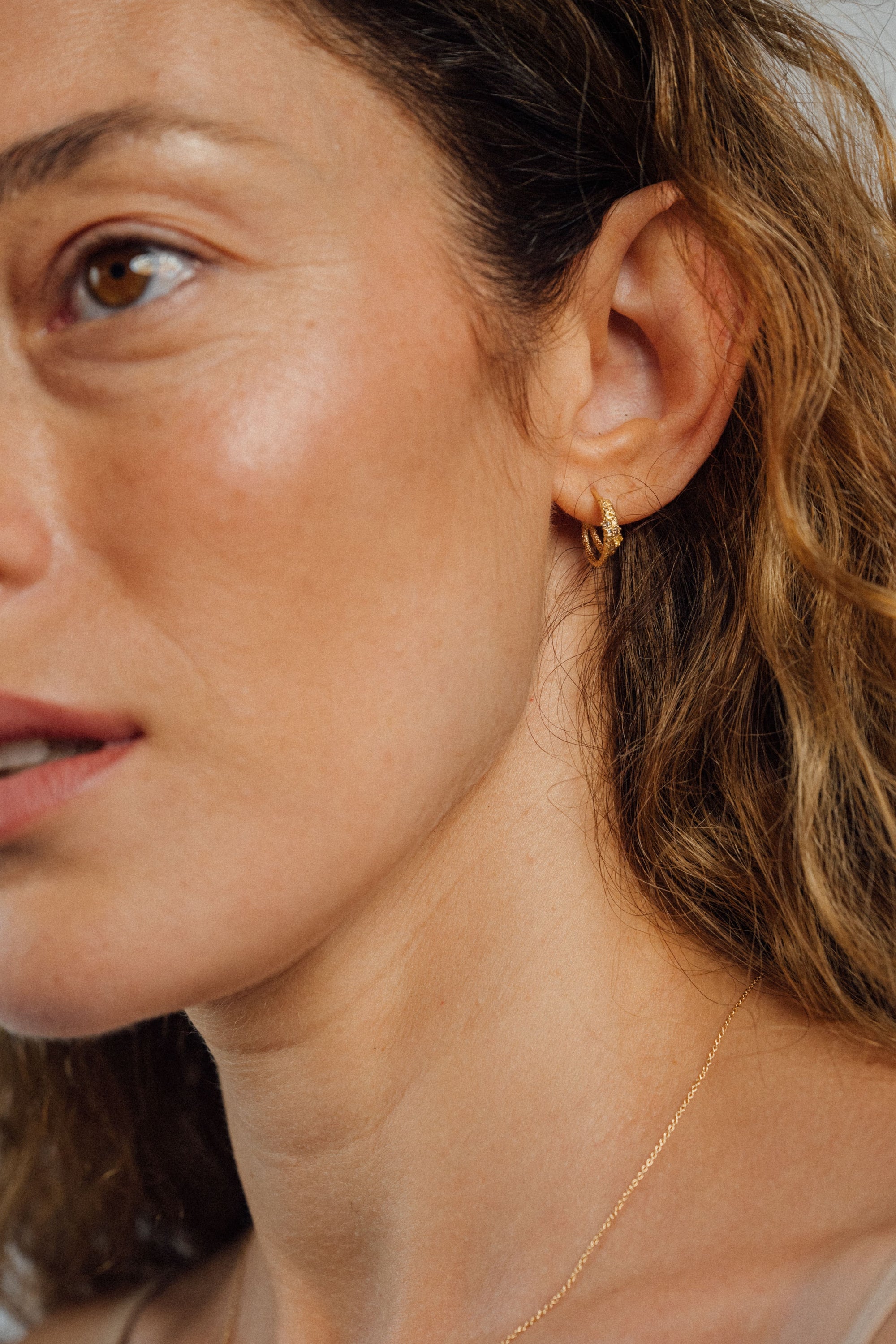 Recycled 18K yellow gold crescent hoop earring that loops together below the lobe, pavé set with brown diamonds and yellow sapphires.