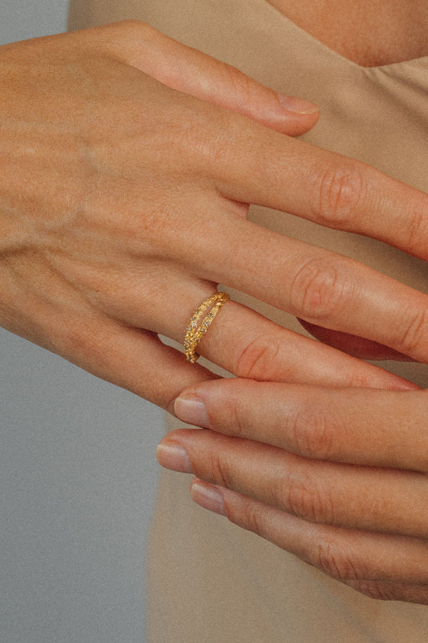 ecycled 18K yellow gold crossover ring with two pavé-set bands of brown diamonds and yellow sapphires, entwined at the top and joined into one band at the bottom. Handcrafted in Bali with stones set in Bangkok.
