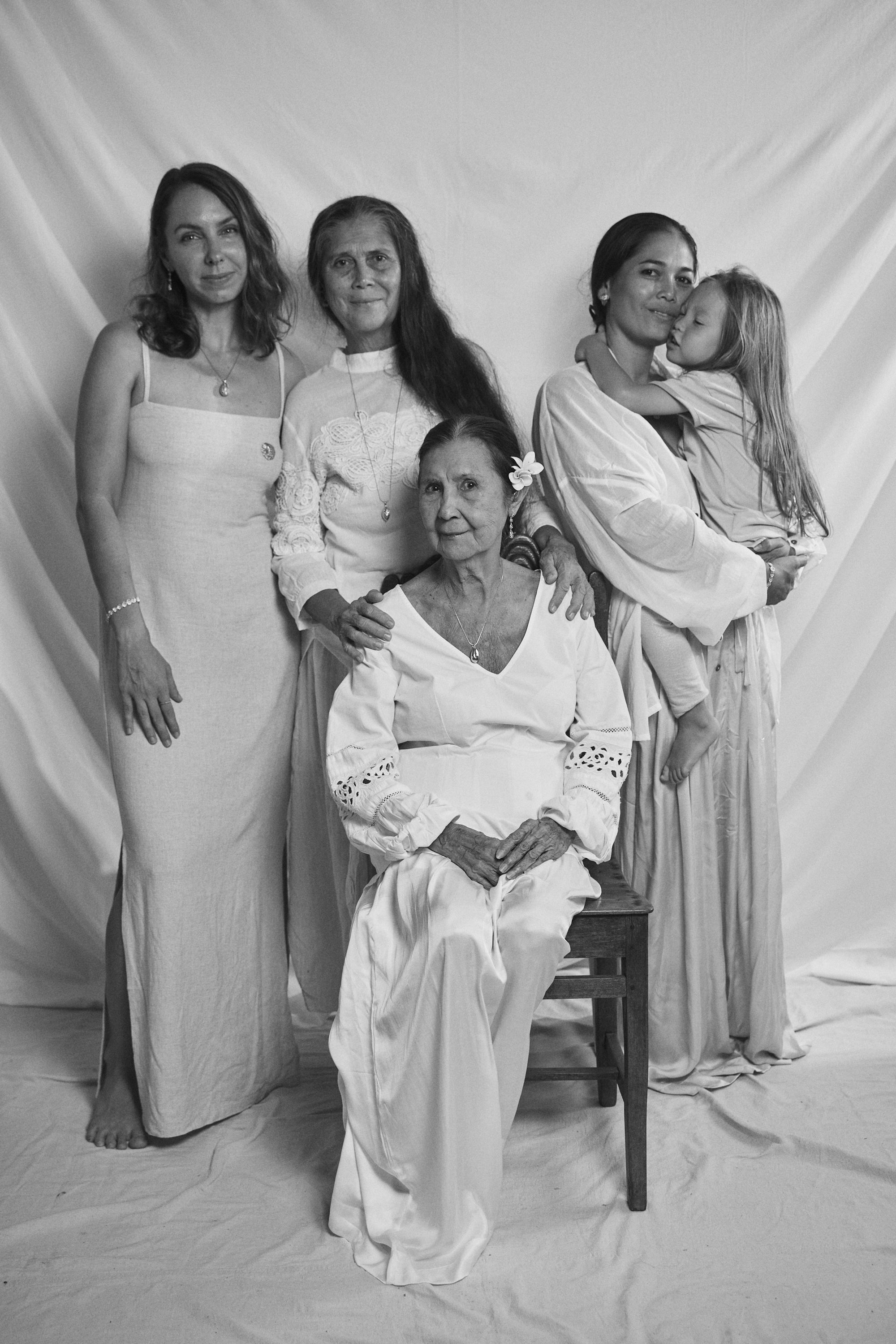 Black and white portrait of three generations of women wearing Carina Hardy fine yellow gold jewelry. Timeless beauty and family bonds. View the collection today.