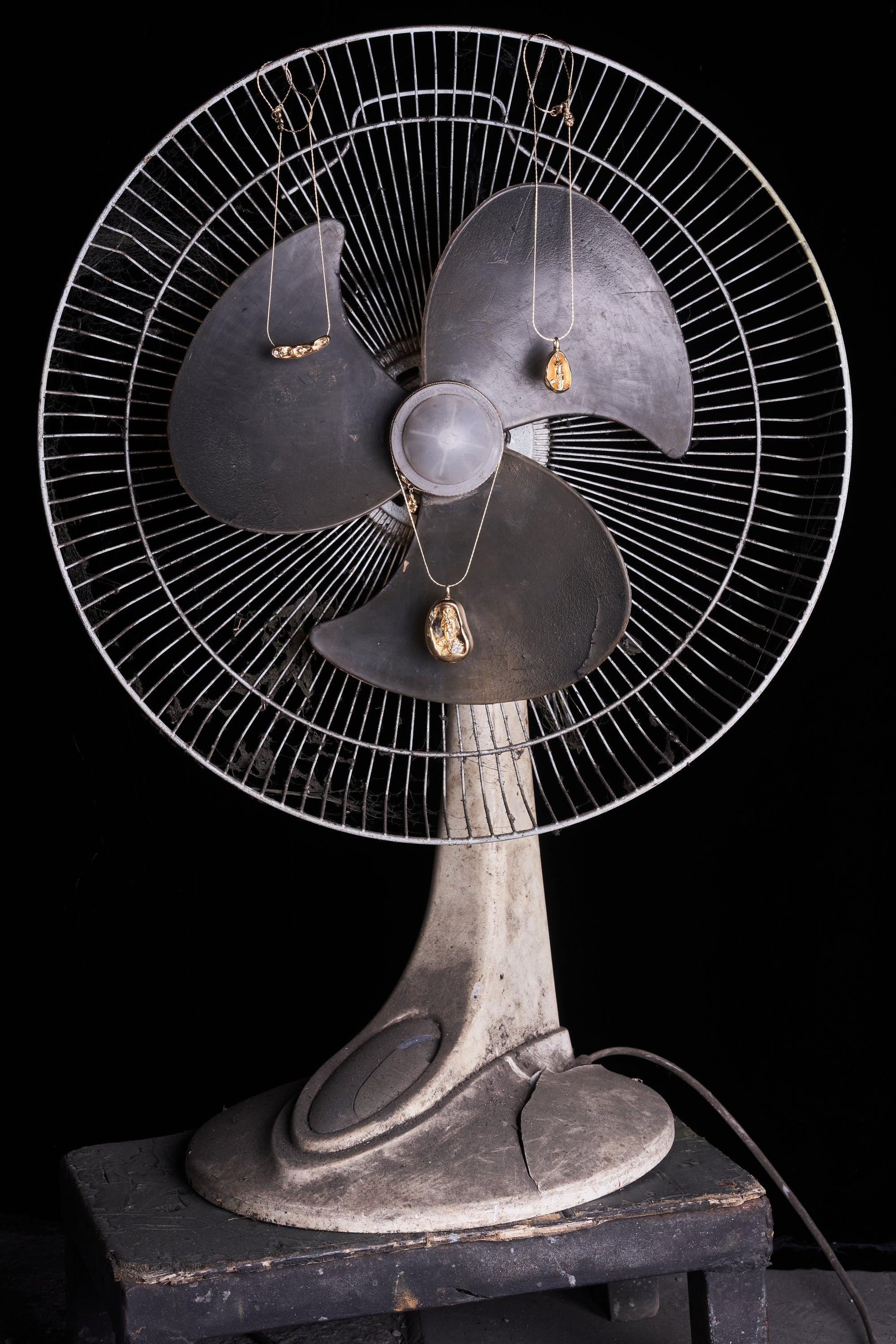 Close-up of a vintage fan with Carina Hardy fine yellow gold necklaces artfully draped. The blend of modern elegance and vintage charm showcased. View the collection today.