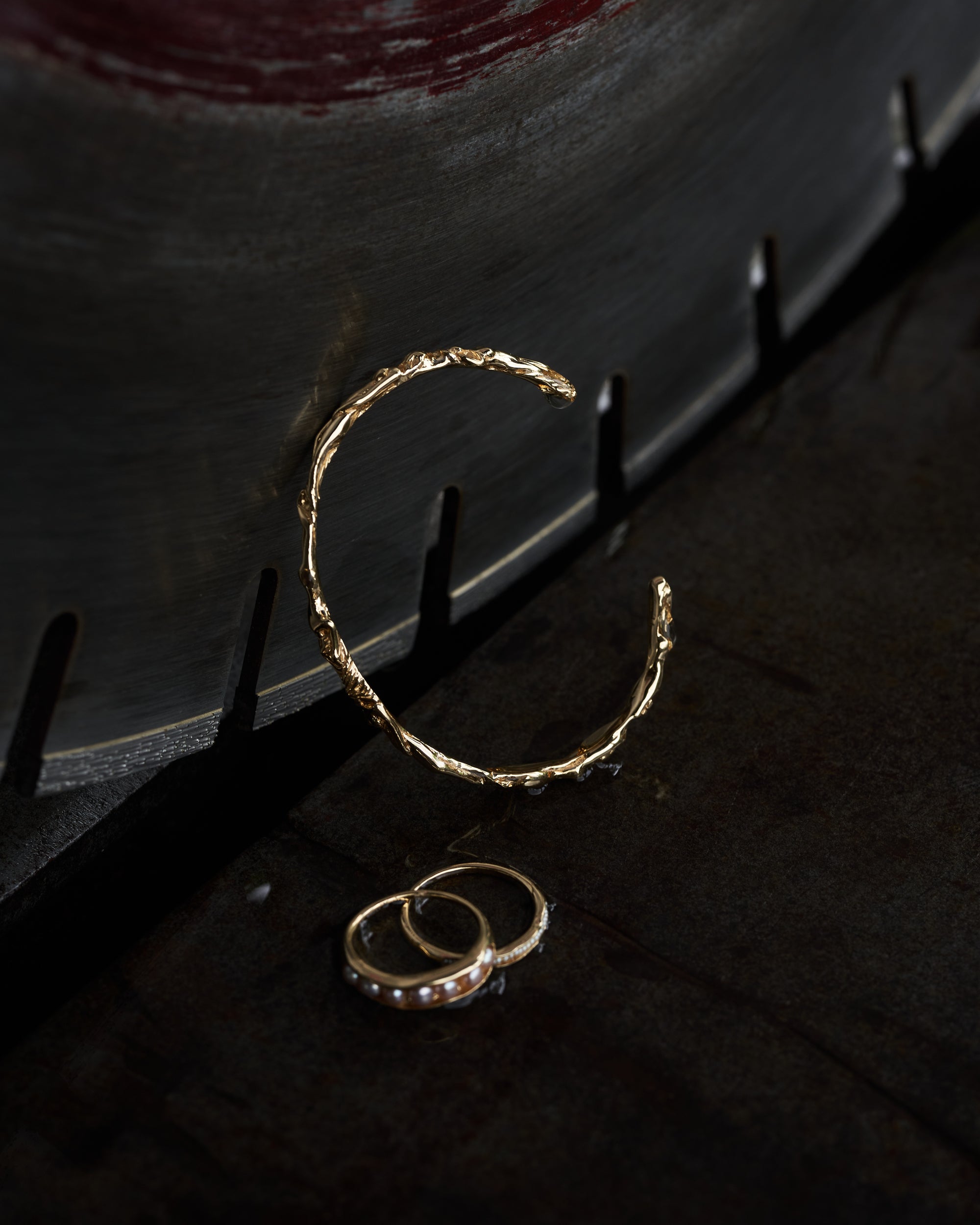 Carina Hardy fine yellow gold rings and cuff, arranged artistically against a dark background. View the collection today.