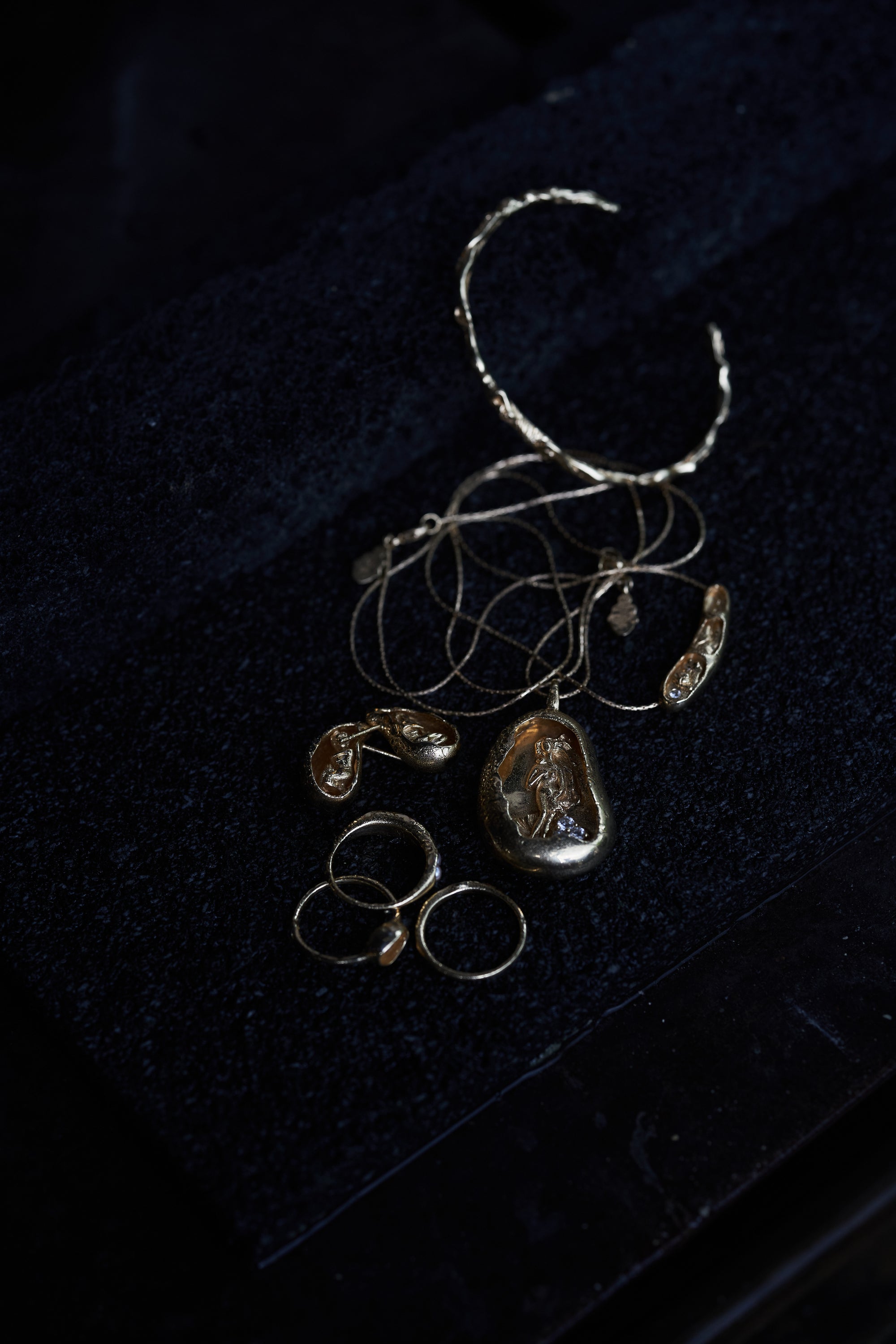 Collection of Carina Hardy fine yellow gold jewelry pieces artfully displayed, representing daily movements on a dark background. View the collection today.