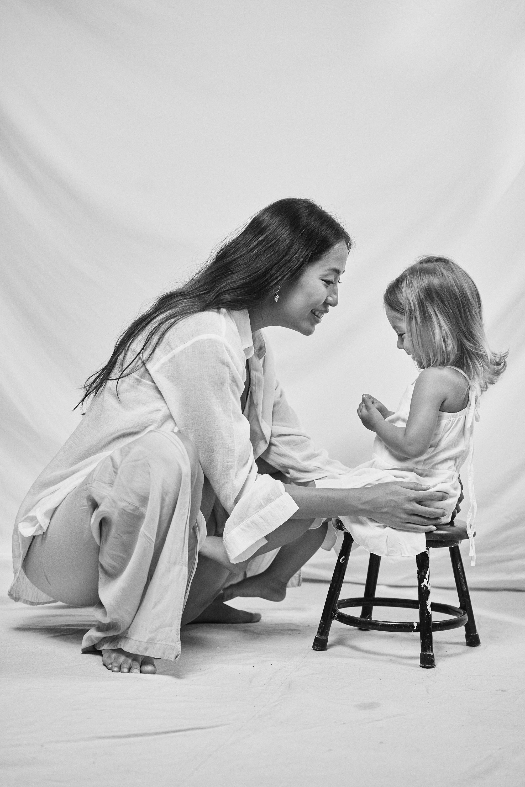 Tender black and white moment of a mother and daughter playing, highlighting Carina Hardy fine yellow gold jewelry.