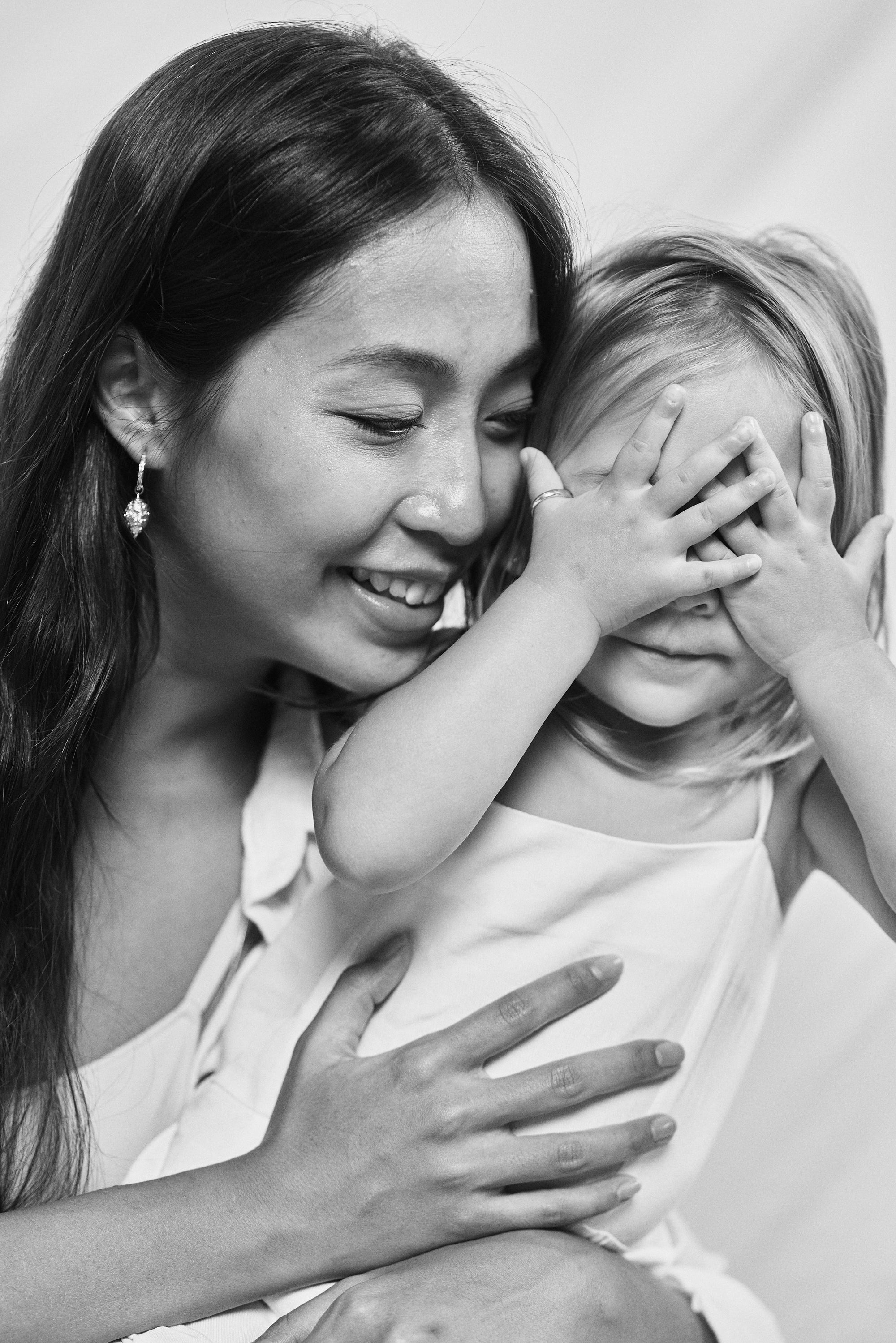 Black and white portrait of a mother and daughter sharing a tender moment, wearing Carina Hardy fine yellow gold jewelry. Their bond and beauty highlighted. View the collection today.