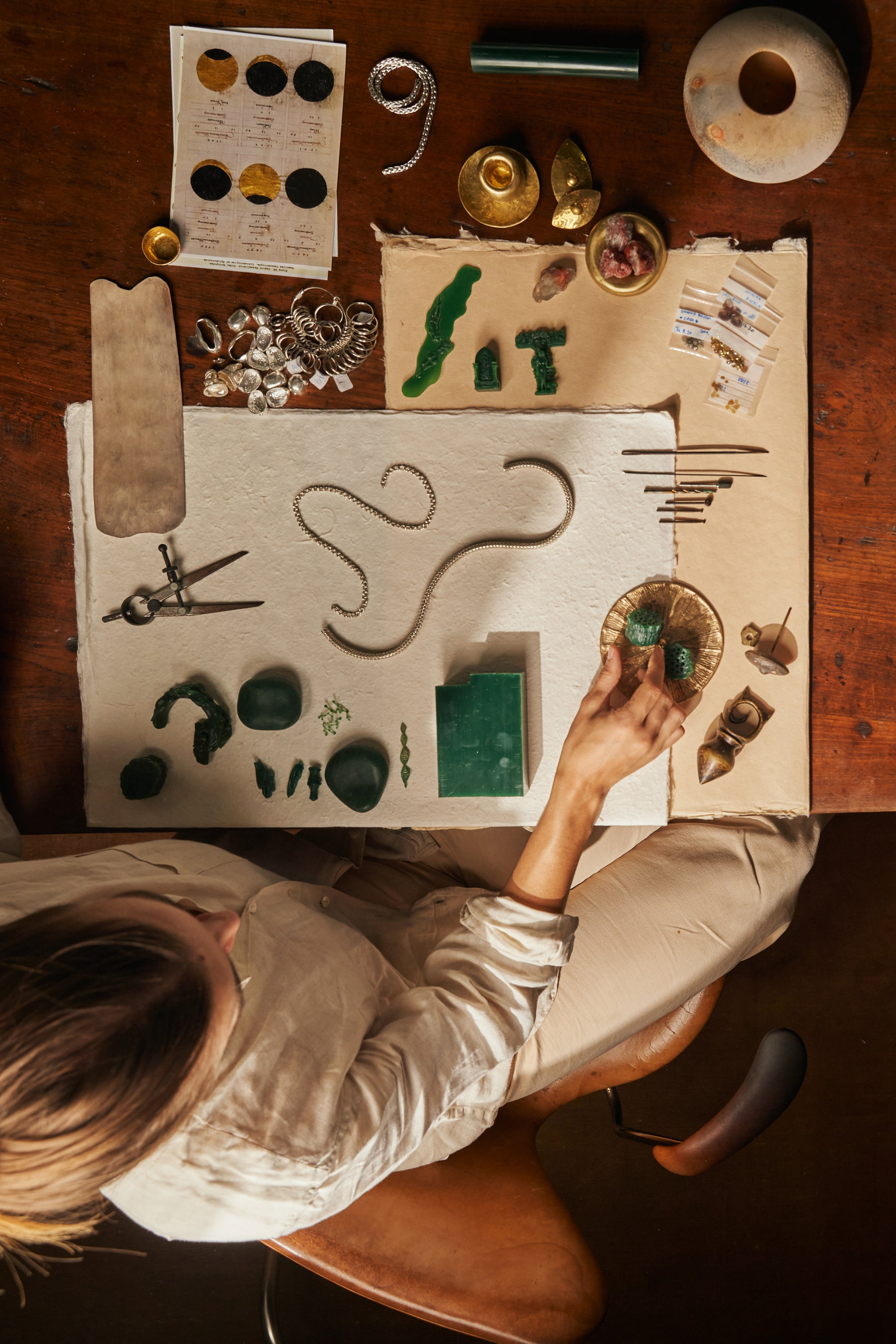 Overhead view of a jewelry designer’s workspace with green wax and tools. Peeking at the craftsmanship behind Carina Hardy’s fine jewelry. View the collection.