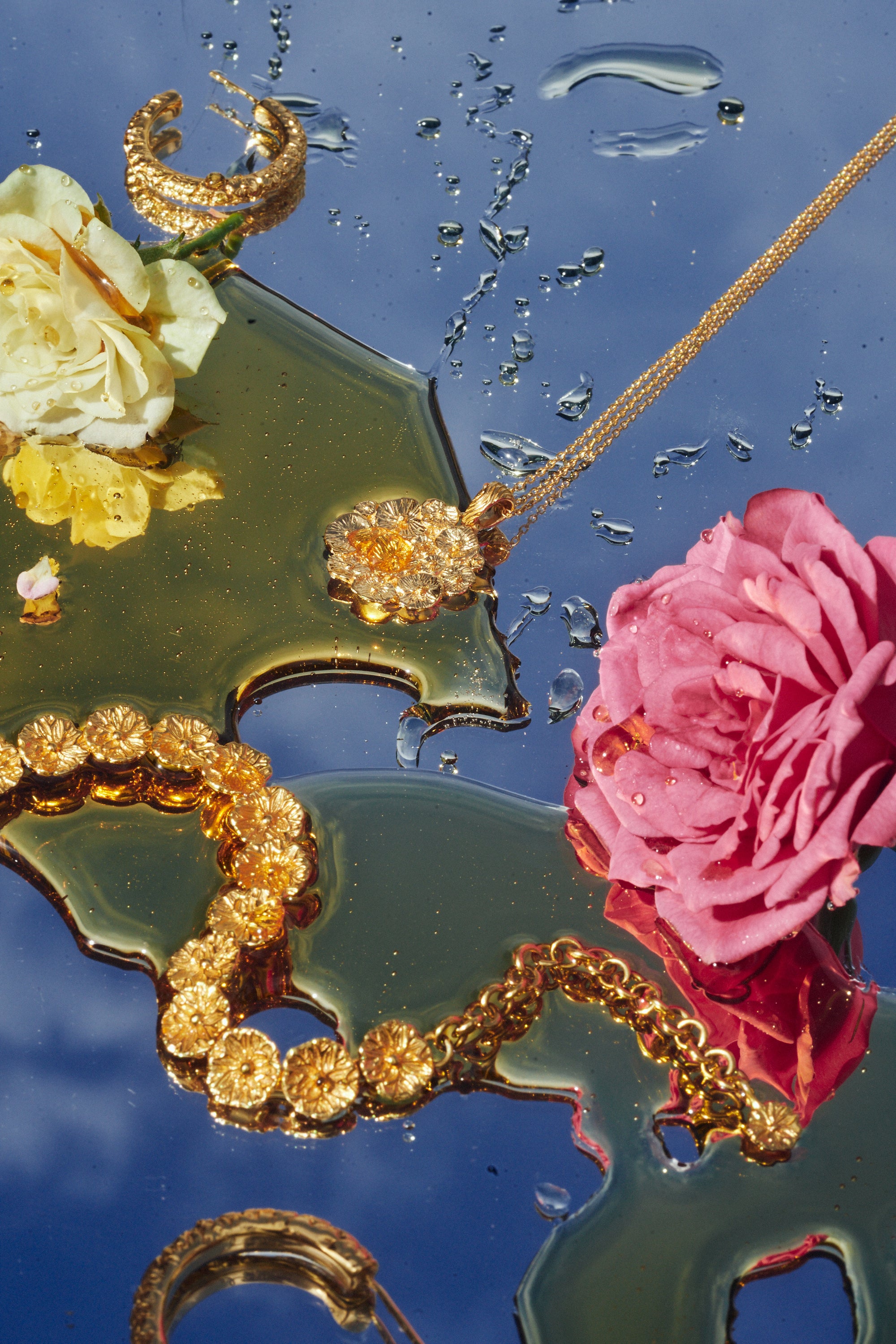 Carina Hardy fine yellow gold jewelry pieces arranged with honey and a pink rose. The nature-inspired design of the collection blending seamlessly with the surrounding.